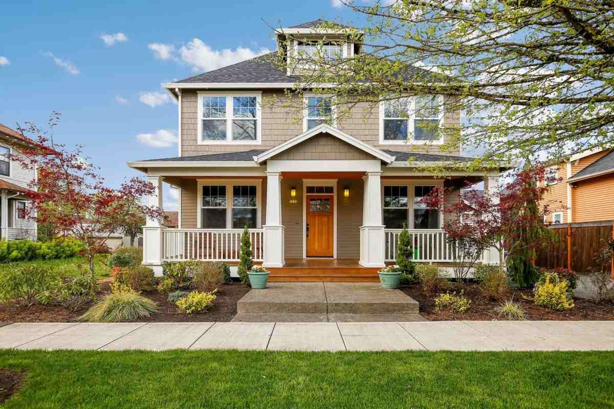 Two story home with wood door and beautiful landscaping