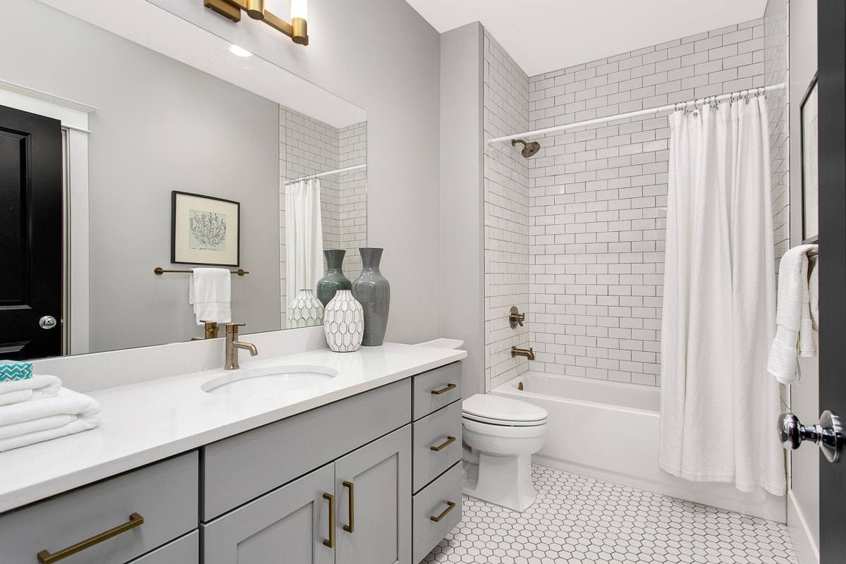 Pristine bathroom with grey cabinets and white tiles