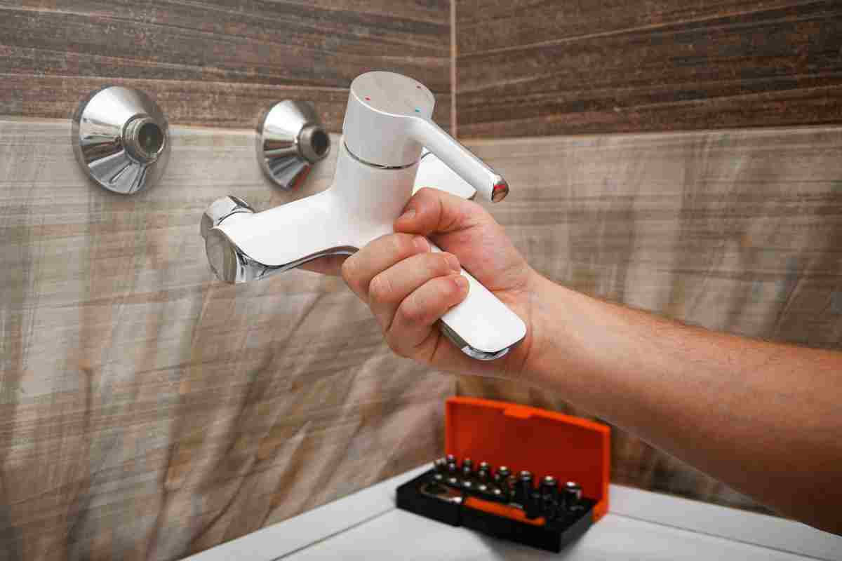 Professional plumber working carefully, installing or repairing bathtub faucet in modern bathroom