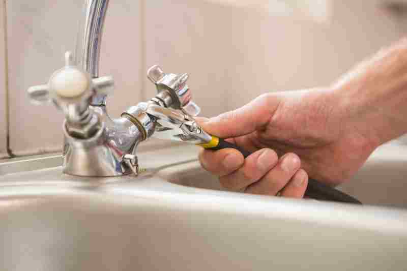 Man fixing tap with pliers