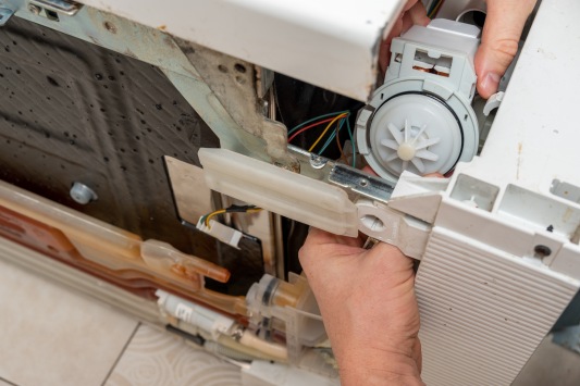 Man installs the new pump in the dishwasher