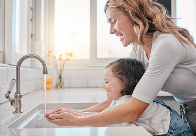 Mother & Daughter Washing Hands From An Air Eductor System