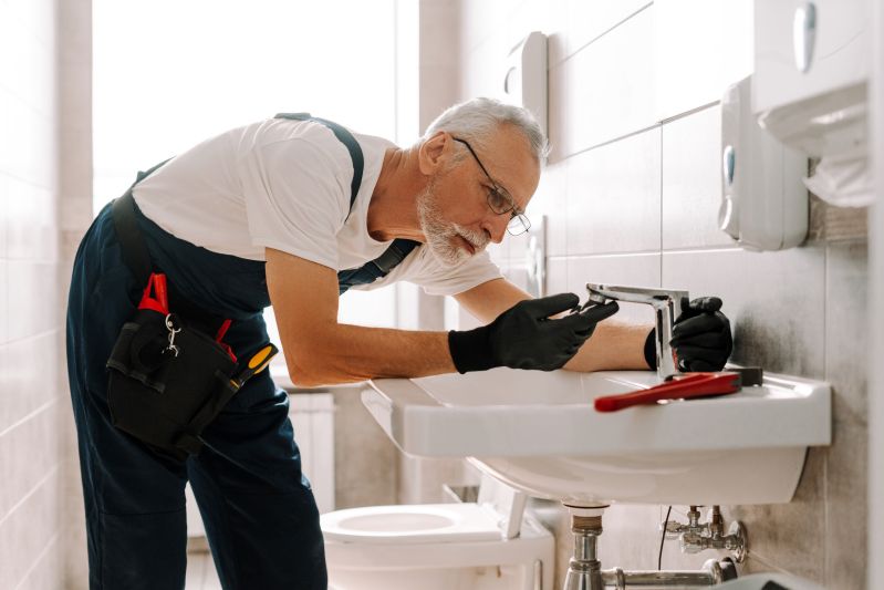 Senior male plumber installing a new faucet in a bathroom