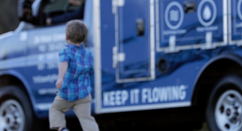 Little Boy Running Next To A Tri-County Pumps Service Truck