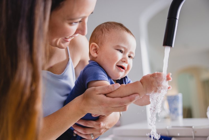 Mother Holding Her Baby While He Gets Water