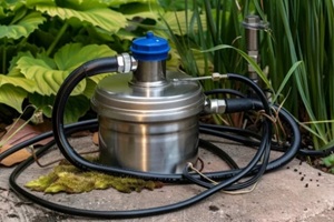 well pump with a long black cable on the background of old grass