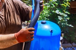 contractor in gloves is fixing artesian water well pump at home, inspecting black hose
