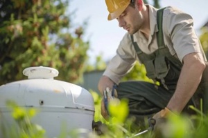 septic system technician inspecting tank in green garden setting