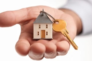 hand presents a tiny model home and a key