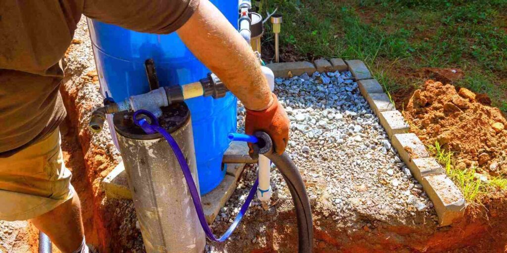 plumber is connecting artesian water well pump in backyard