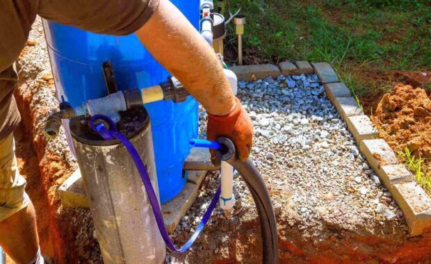 plumber is connecting artesian water well pump in backyard