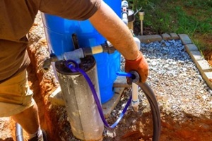 plumber is connecting artesian water well pump in backyard