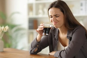 disgusted woman smelling expired coffee at home