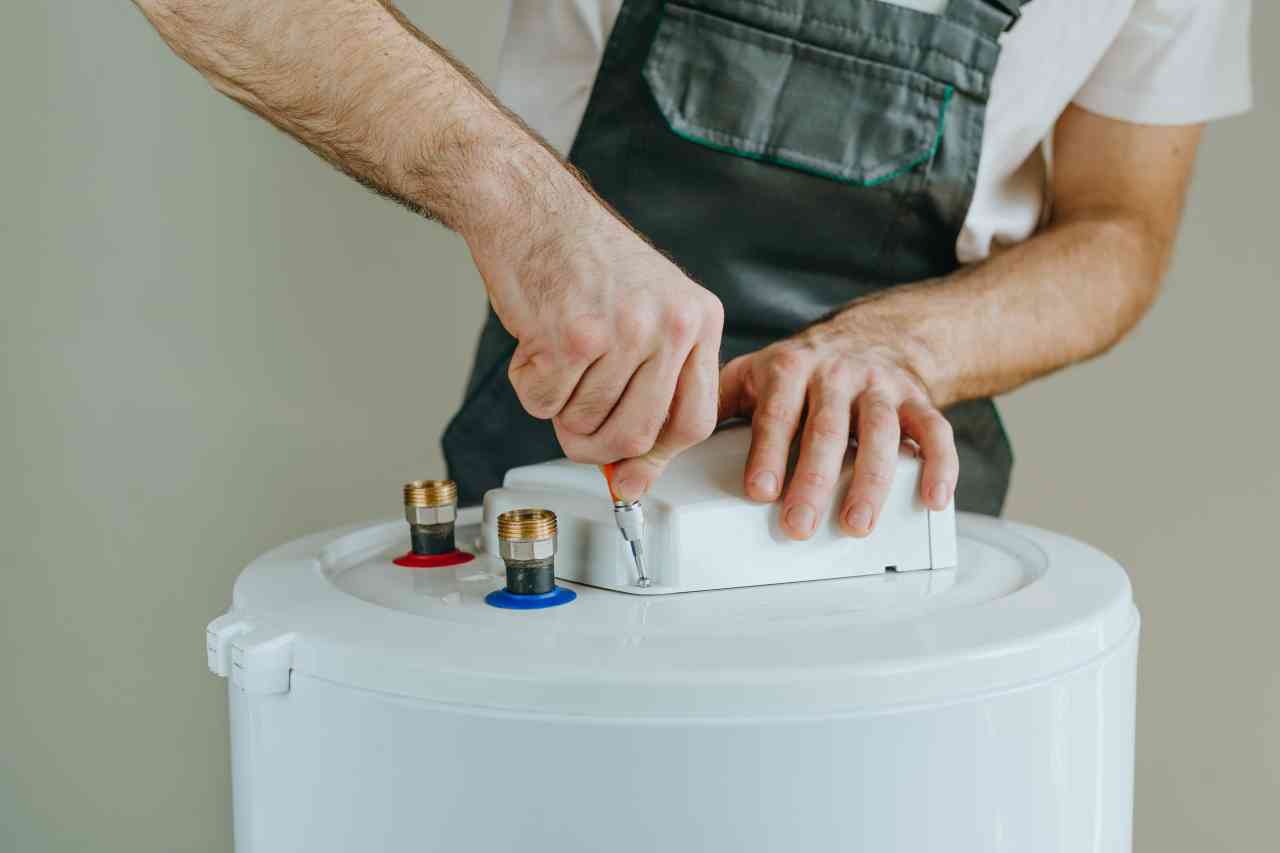 Technician tightening screws on the electric water heater, focusing on repair and maintenance