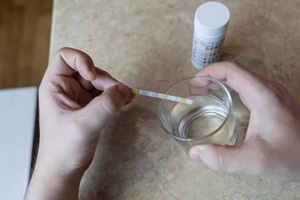 man in the kitchen tests tap water quality with a test strip