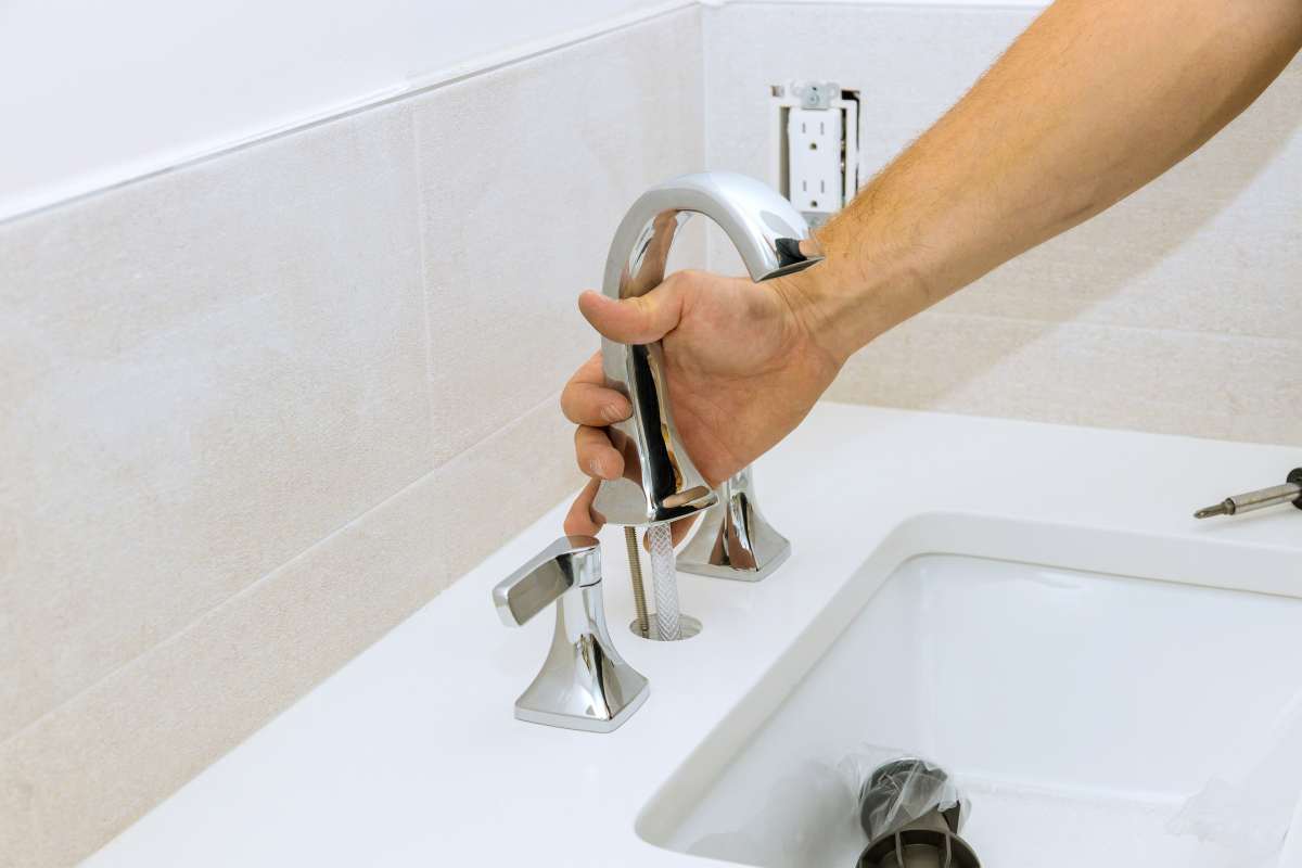 The plumber at work assembles and installs the water faucet in the bathroom