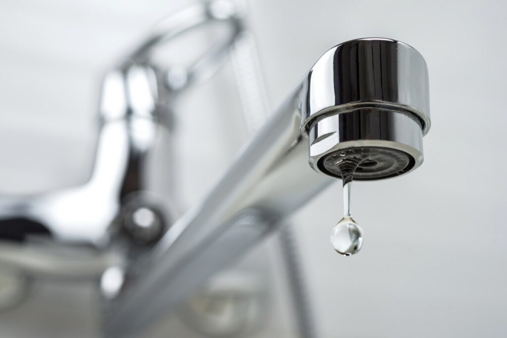 A drop of pure water dripping from the tap. Selective focus.