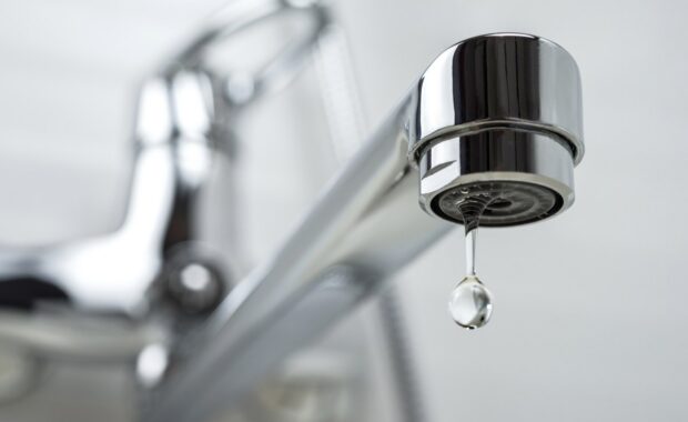 A drop of pure water dripping from the tap. Selective focus.