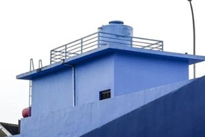 minimalist shot of a bright blue industrial rooftop featuring a large water storage tank