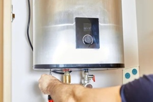 the man tightens the pipe nut in the water heating system