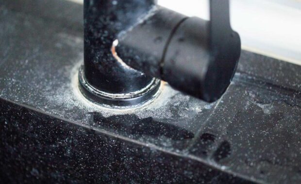 White scale from hard water on black bathroom faucets