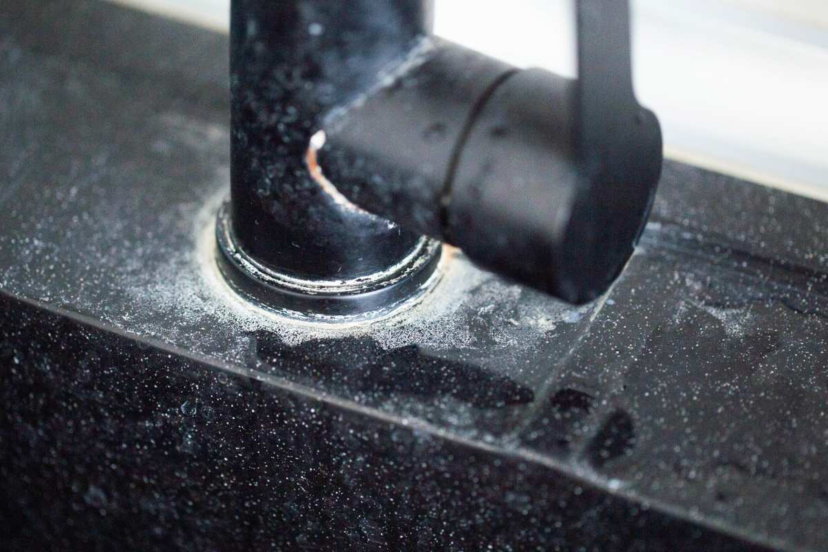 White scale from hard water on black bathroom faucets