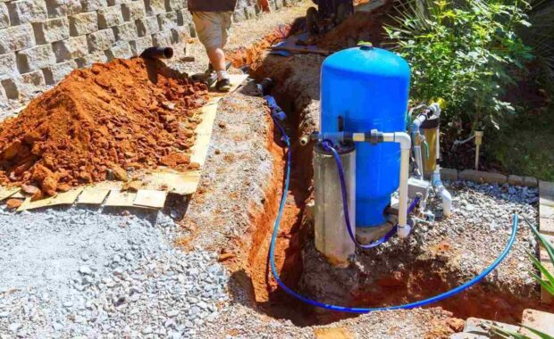 homeowner works on installing water well pump system near trench in thoughtfully arranged outdoor space