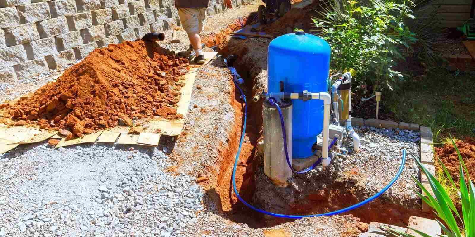 homeowner works on installing water well pump system near trench in thoughtfully arranged outdoor space