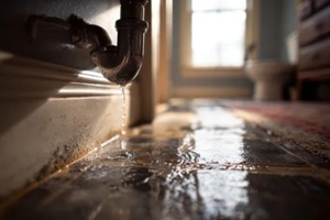 indoor water damage from a leaking pipe with a wet floor and damp walls