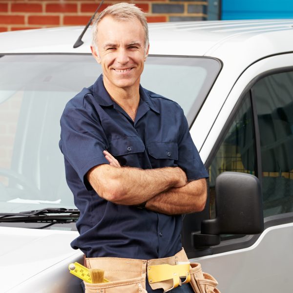 plumber wearing a utility belt by their truck outside of a maryland home