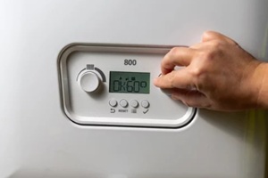 men hand setting temperature button on control panel of central heating at combi boiler