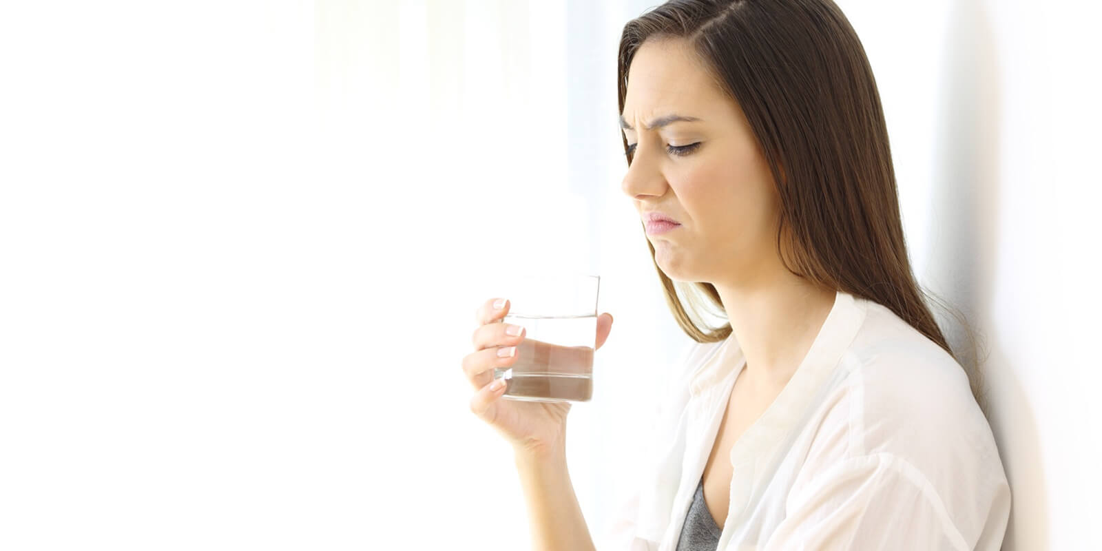 disgusted woman drinking water with bad taste on white